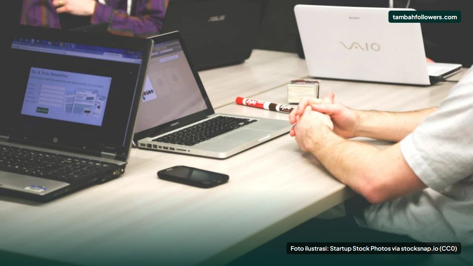 Tim kecil bekerja bersama dengan beberapa laptop di satu meja kantor